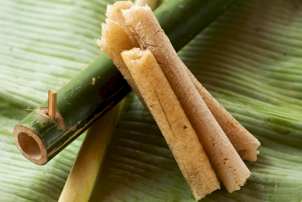 Fragrant rice steams inside fresh bamboo tubes over an open fire, showcasing Pu Luong's signature cooking method 